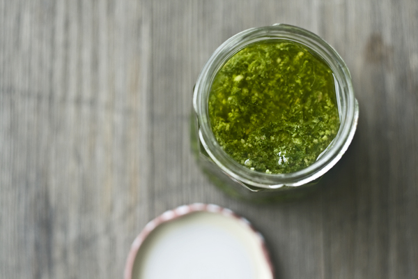 Ein Glas giftgrünes Bärlauch-Sesam-Pesto steht auf einem Holztisch