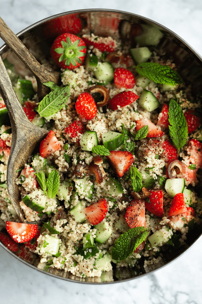 Eine Schüssel Couscous Salat mit Erdbeeren steht auf einem weißen Tisch