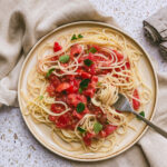 Ein Teller Spaghetti mit roher Tomatensauce und Oregano-Blättchen