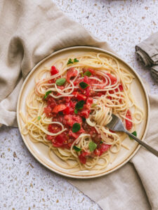 Ein Teller Spaghetti mit roher Tomatensauce und Oregano-Blättchen